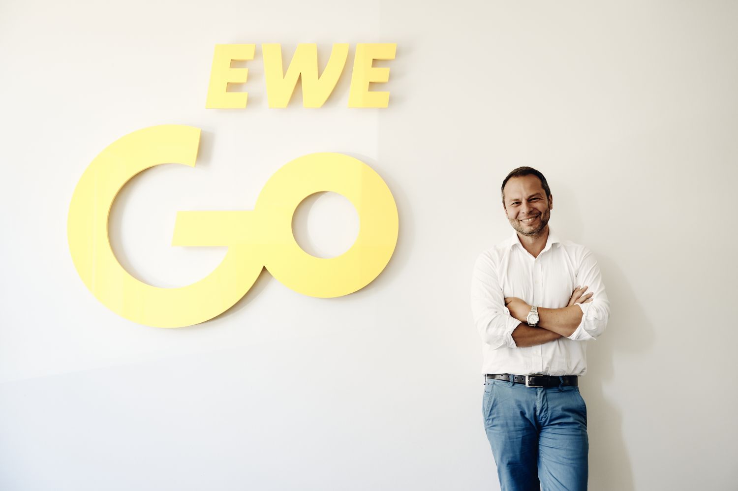 Ilker Akkaya, Geschäftsführer von EWE Go steht vor Logo-Schriftzug EWE Go